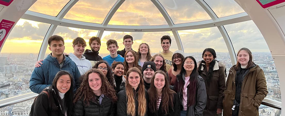 A large group of Purdue Honors College students poses for a photo inside a glass observation capsule of the London Eye, with the city skyline visible in the background.